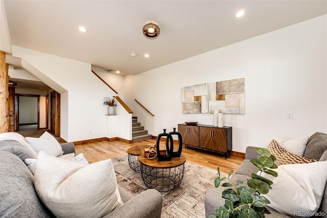 living room featuring stairs, light wood-style floors, baseboards, and recessed lighting