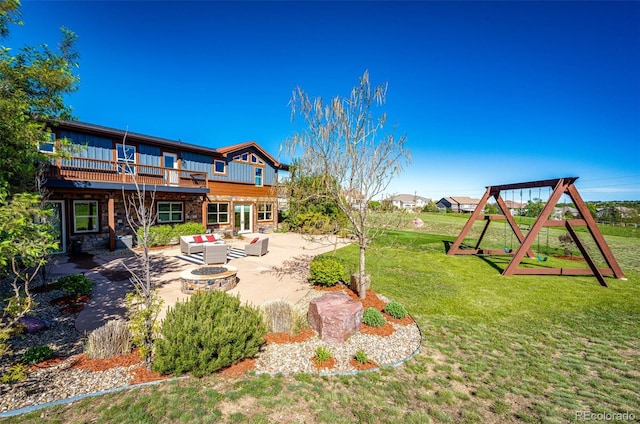 view of grassy yard featuring a patio, an outdoor living space with a fire pit, a wooden deck, and a playground