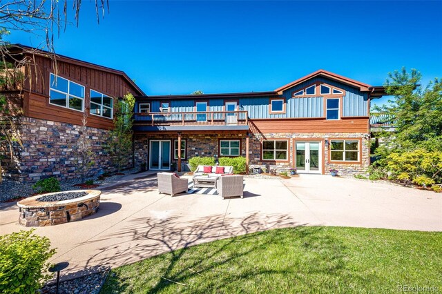 rear view of house featuring french doors, stone siding, a patio area, and a balcony
