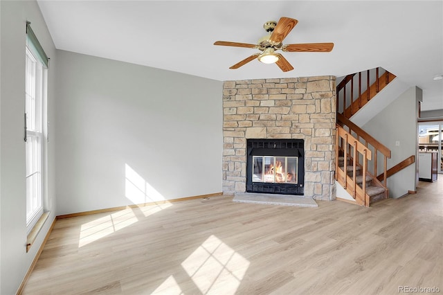 unfurnished living room featuring ceiling fan, a stone fireplace, and light hardwood / wood-style flooring