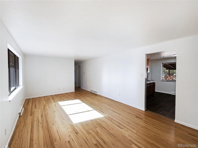 empty room with light hardwood / wood-style flooring and a baseboard radiator