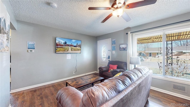 living area featuring baseboards, a textured ceiling, wood finished floors, and a ceiling fan