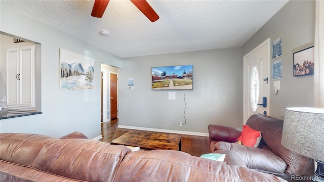 living area featuring wood finished floors, a ceiling fan, baseboards, and a textured ceiling
