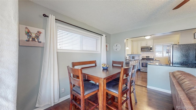 dining area featuring dark wood finished floors, ceiling fan, baseboards, and a textured ceiling