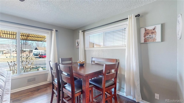 dining area featuring baseboards, a textured ceiling, and wood finished floors