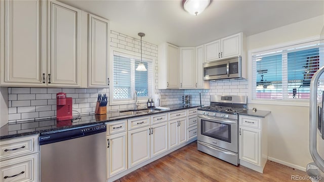 kitchen with light wood-style flooring, a sink, backsplash, white cabinetry, and appliances with stainless steel finishes