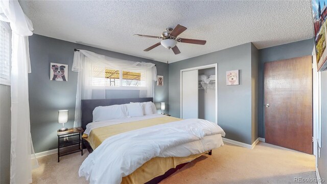 bedroom with ceiling fan, baseboards, carpet floors, a closet, and a textured ceiling
