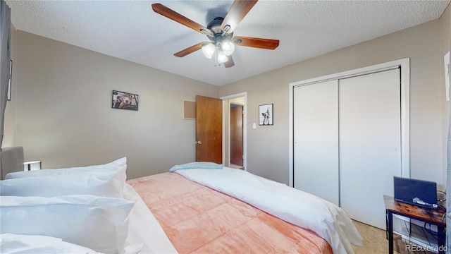 bedroom with ceiling fan, light colored carpet, a closet, and a textured ceiling