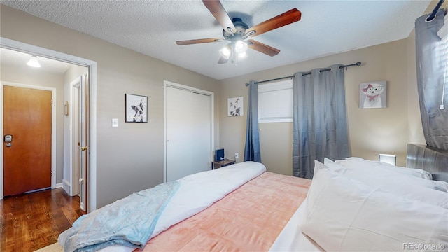 bedroom featuring ceiling fan, a closet, a textured ceiling, and wood finished floors
