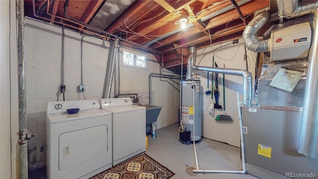 clothes washing area featuring gas water heater, a sink, laundry area, and washer and dryer