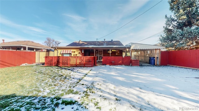snow covered house featuring a deck and fence