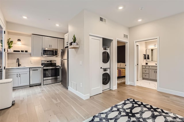 4025 Jason St Unit 101, Denver, CO 80211 - kitchen with appliances with stainless steel finishes, estacked washer and dryer, light wood finished floors, backsplash, and open shelves