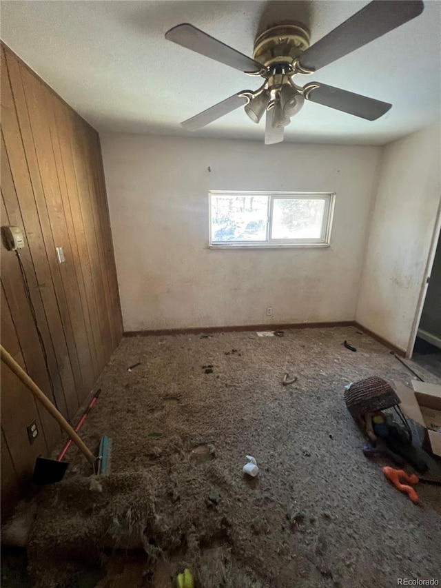 spare room featuring ceiling fan and wood walls