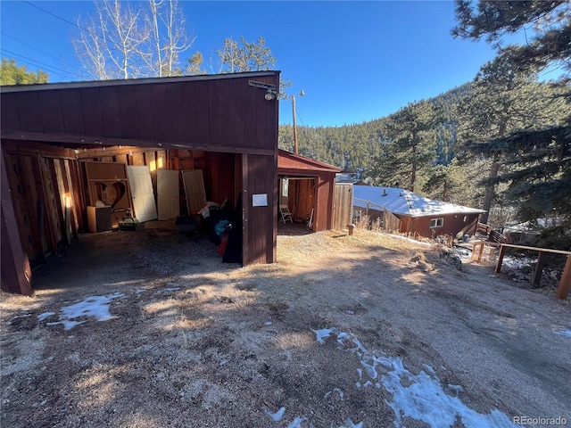 view of side of home featuring a mountain view and an outbuilding