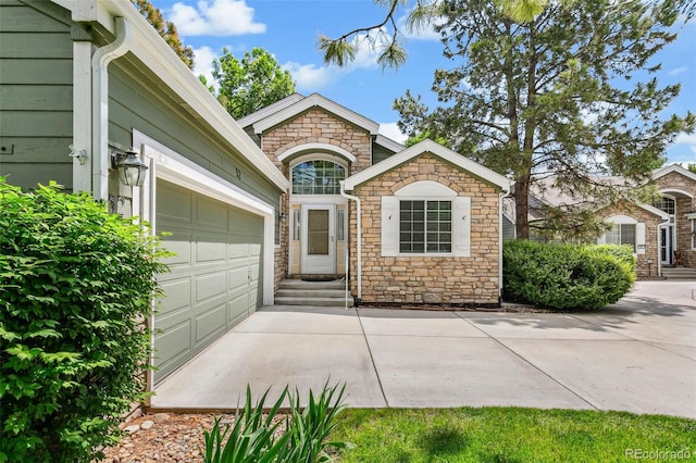 7400 W Grant Ranch Blvd Unit 52, Littleton, CO 80123 - view of front of house featuring stone siding, driveway, an attached garage, and entry steps