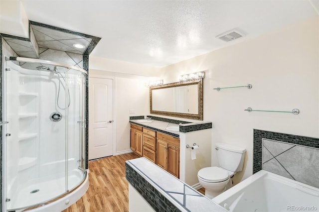7400 W Grant Ranch Blvd Unit 52, Littleton, CO 80123 - bathroom featuring a shower stall, double vanity, wood finished floors, a jetted tub, and a textured ceiling