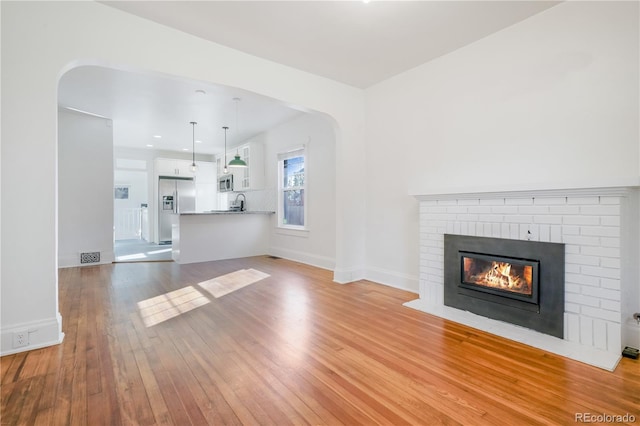 unfurnished living room with light hardwood / wood-style floors and a brick fireplace