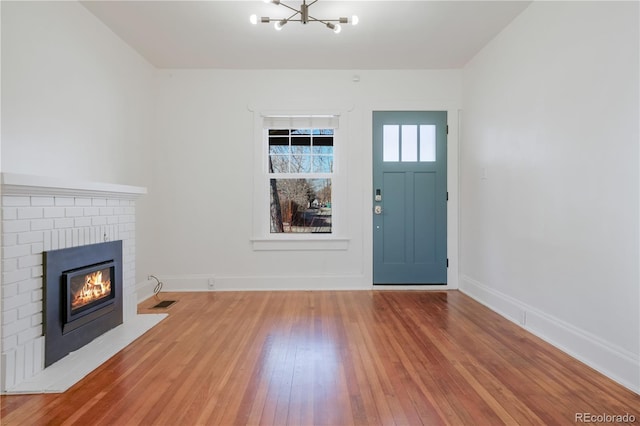 entryway featuring hardwood / wood-style floors, a chandelier, and a brick fireplace