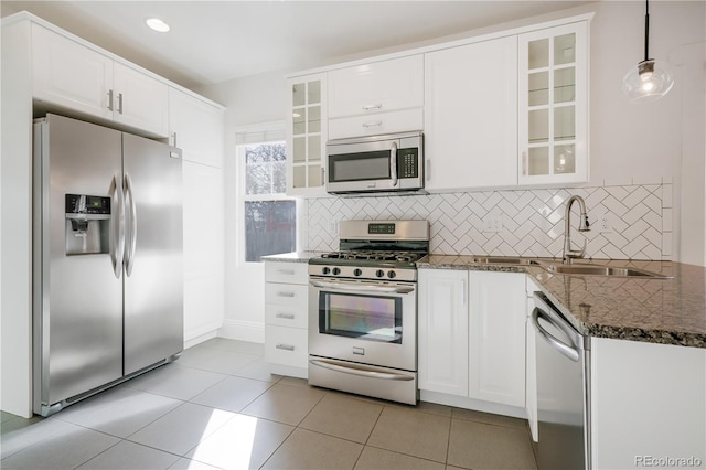 kitchen featuring stainless steel appliances, tasteful backsplash, white cabinets, decorative light fixtures, and dark stone counters