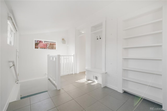 mudroom with lofted ceiling, built in shelves, and tile patterned floors