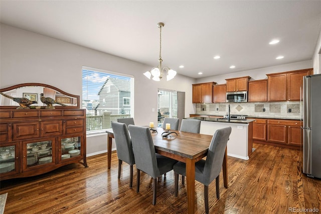 dining space with dark wood-type flooring, sink, and an inviting chandelier