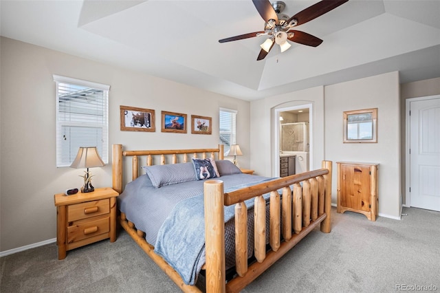 carpeted bedroom featuring ceiling fan, ensuite bathroom, and a raised ceiling