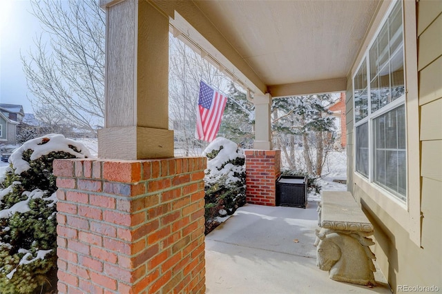 snow covered patio featuring covered porch