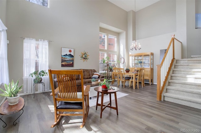 living area featuring a high ceiling, wood-type flooring, and an inviting chandelier