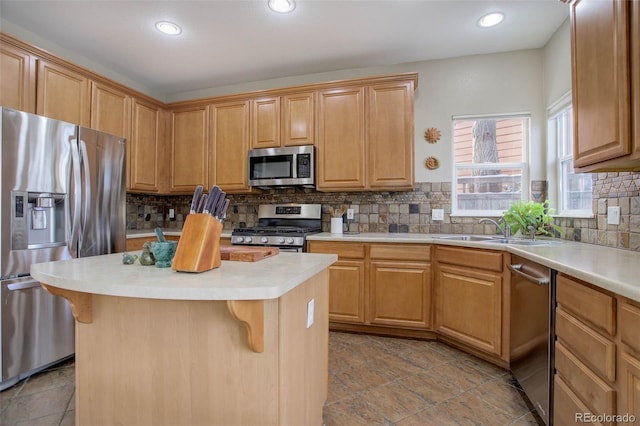 kitchen featuring appliances with stainless steel finishes, a center island, a kitchen bar, tasteful backsplash, and sink