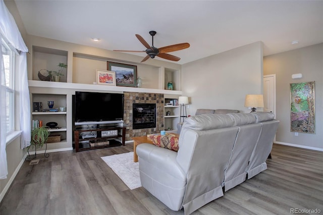 living room with built in features, hardwood / wood-style flooring, and ceiling fan