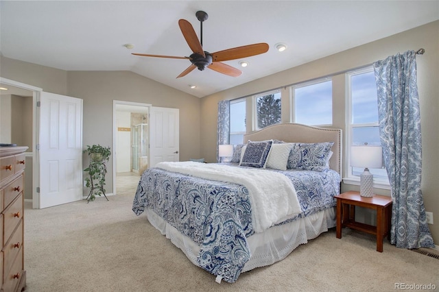 bedroom featuring ceiling fan, light colored carpet, lofted ceiling, and ensuite bathroom