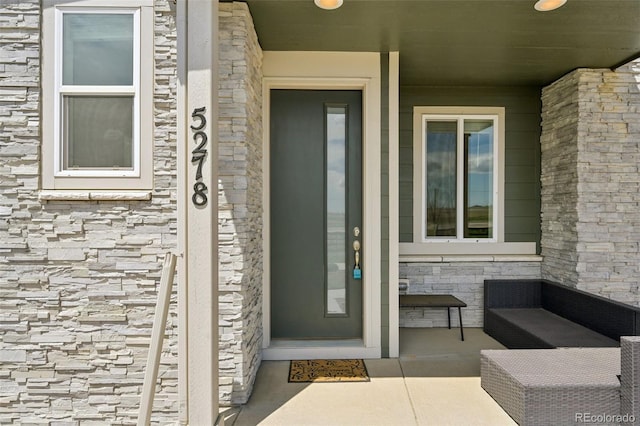 doorway to property featuring a porch and stone siding