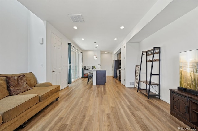 living room featuring recessed lighting, light wood-type flooring, and visible vents