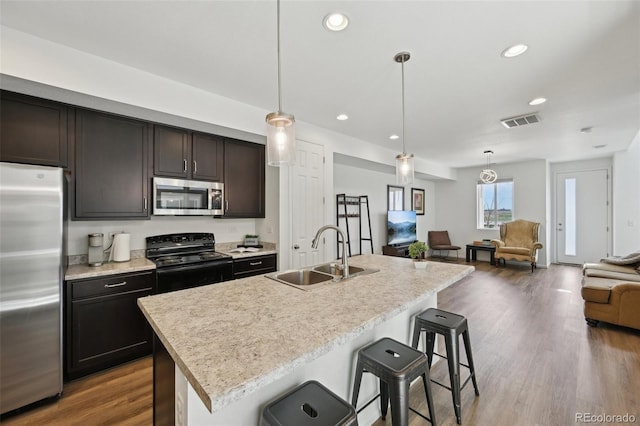kitchen featuring appliances with stainless steel finishes, a sink, light countertops, recessed lighting, and open floor plan