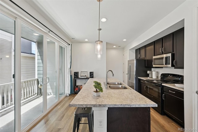 kitchen with light wood-style floors, a sink, a breakfast bar area, and stainless steel appliances