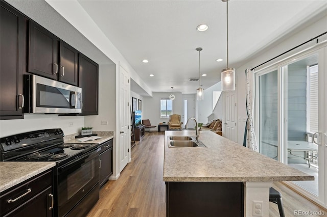 kitchen featuring a sink, stainless steel microwave, open floor plan, light wood-style floors, and black range with electric cooktop