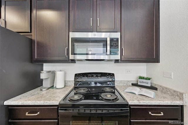 kitchen featuring dark brown cabinets, stainless steel microwave, and black range with electric stovetop