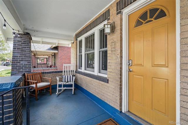 view of exterior entry with covered porch and brick siding