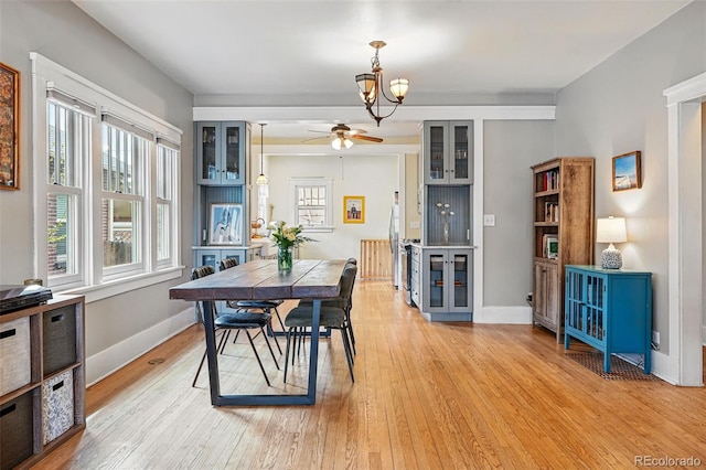 dining room with light wood-style floors, baseboards, and ceiling fan with notable chandelier