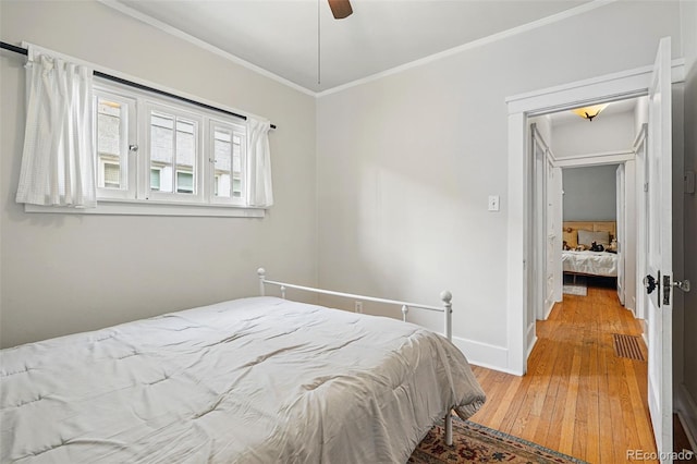 bedroom featuring light wood-style flooring, baseboards, ornamental molding, ceiling fan, and visible vents