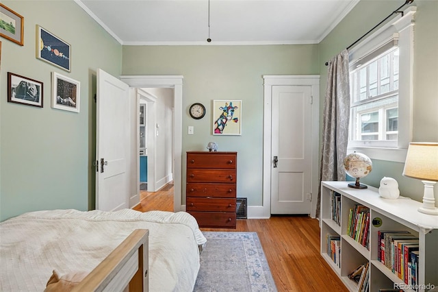 bedroom with baseboards, ornamental molding, and light wood-style flooring