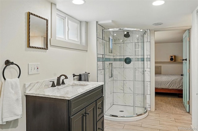 bathroom featuring vanity, wood finished floors, a shower stall, and recessed lighting