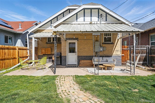back of property with a yard, a patio area, brick siding, and a fenced backyard