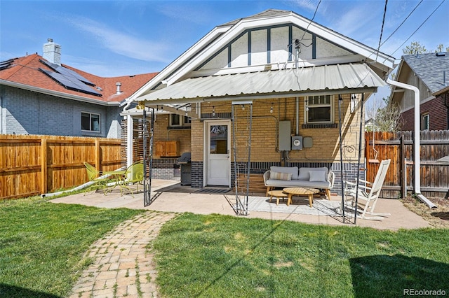 back of house with a fenced backyard, a patio, brick siding, and a lawn