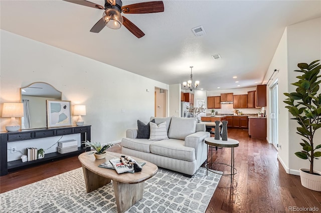 living room with ceiling fan with notable chandelier and dark wood-type flooring