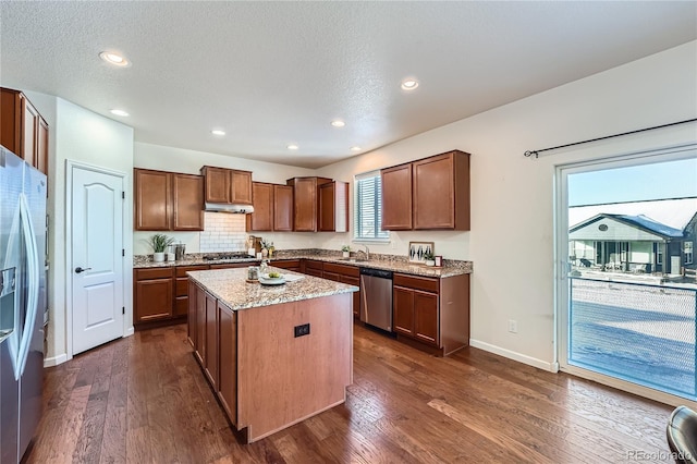 kitchen featuring sink, dark hardwood / wood-style flooring, a textured ceiling, a kitchen island, and appliances with stainless steel finishes