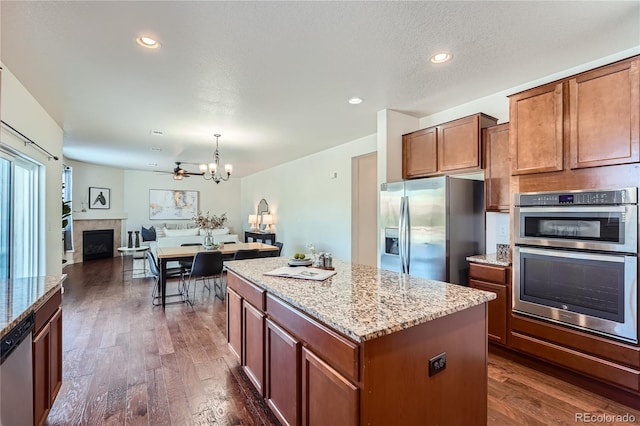 kitchen with pendant lighting, a center island, dark hardwood / wood-style floors, a textured ceiling, and stainless steel appliances