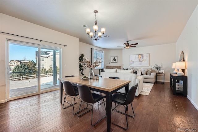 dining room with ceiling fan with notable chandelier and dark hardwood / wood-style floors