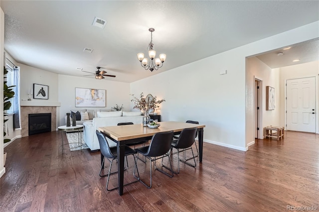 dining space with dark wood finished floors, visible vents, a tiled fireplace, and baseboards