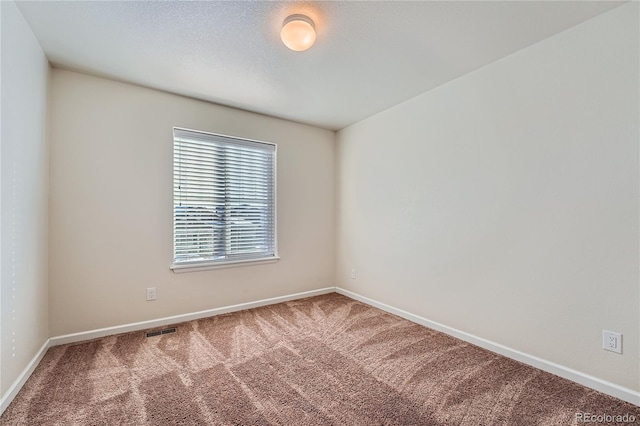 spare room featuring visible vents, baseboards, and carpet